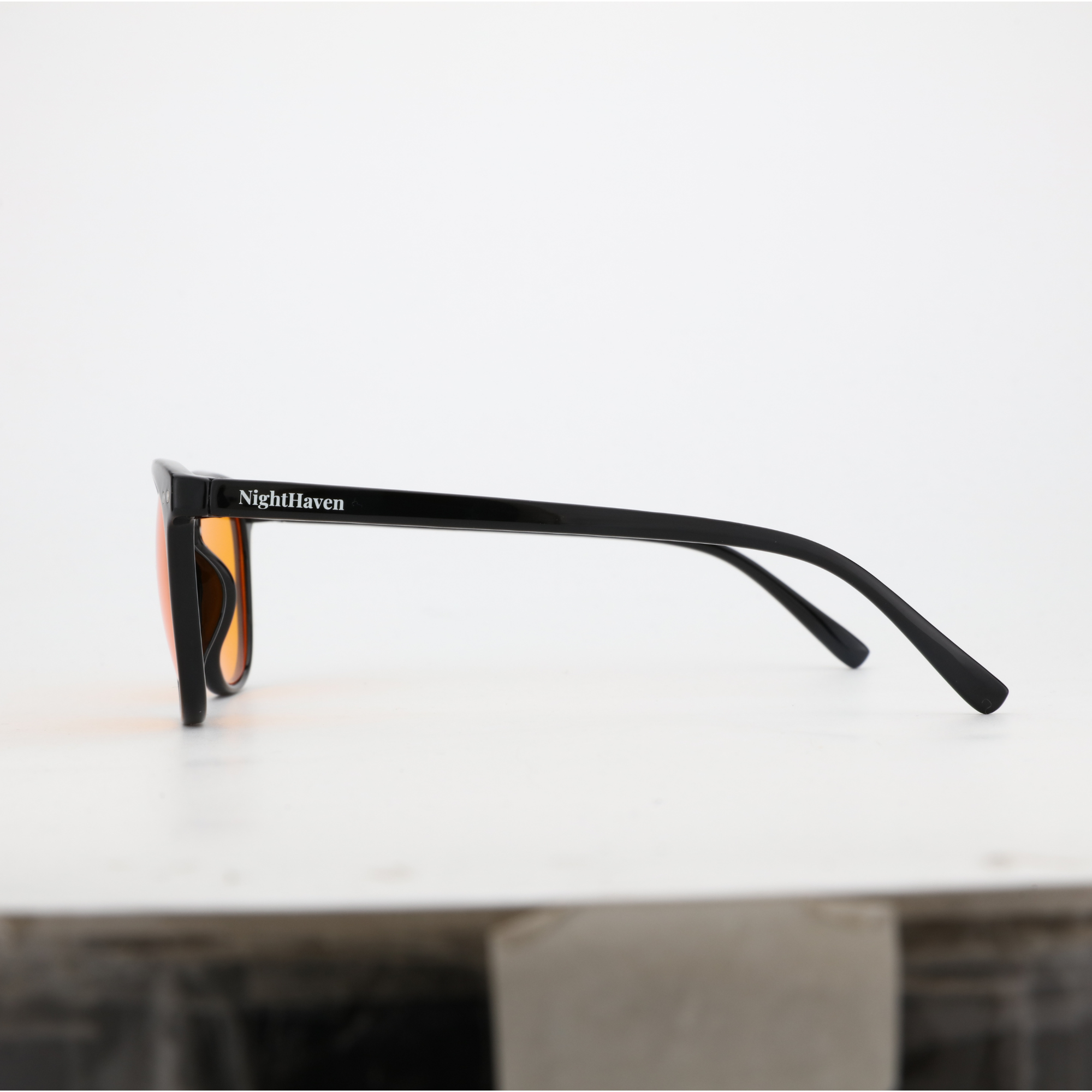 Seitenansicht NightHaven VESPER™ Amber Lense – schlanker glänzend-schwarzer Bügel mit NightHaven-Schriftzug und orangefarbenem Glas