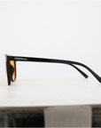 Seitenansicht NightHaven VESPER™ Amber Lense – schlanker glänzend-schwarzer Bügel mit NightHaven-Schriftzug und orangefarbenem Glas